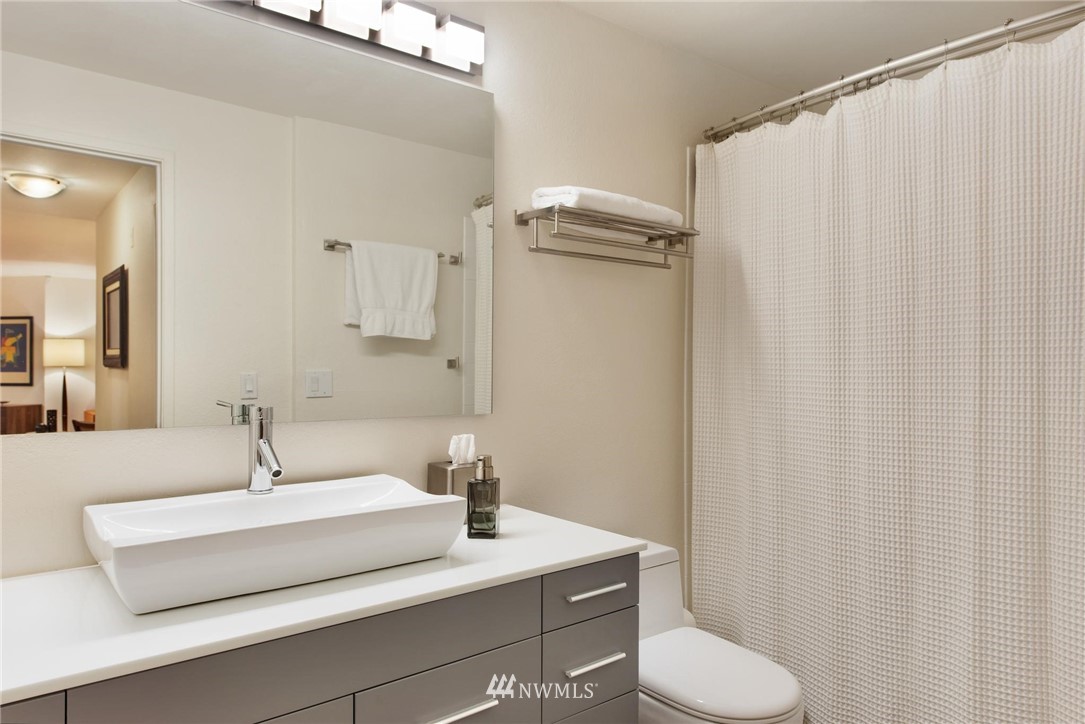 2244 13th Avenue West, Unit 115 Seattle, WA 98119 - Photo 14 of 19 a bathroom with a sink a toilet a mirror and shower curtain