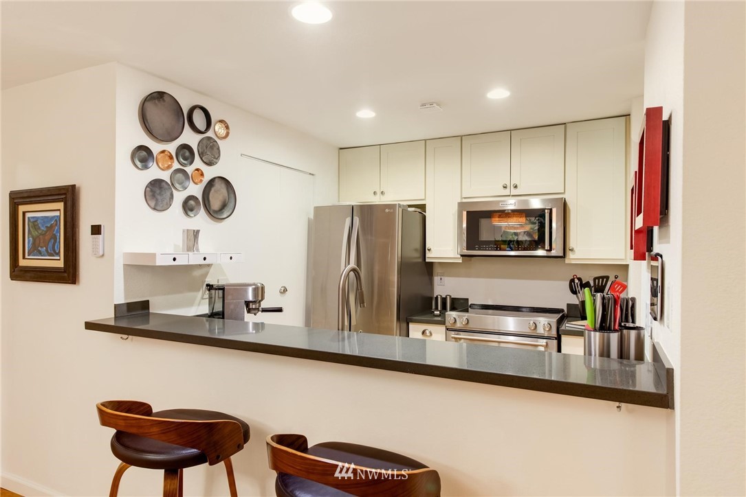 2244 13th Avenue West, Unit 115 Seattle, WA 98119 - Photo 8 of 19 a kitchen with stainless steel appliances granite countertop a sink and a microwave