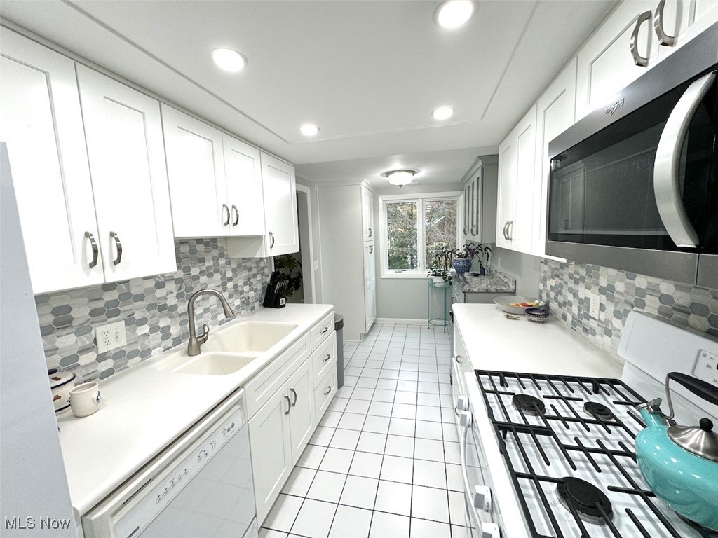 3701 Mayfield Road, Unit 207 Cleveland, OH 44121 - Photo 11 of 30 Kitchen featuring white cabinets, white appliances, sink, and backsplash