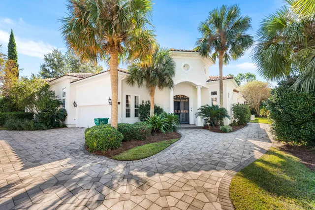 a view of a white house with a yard and palm trees