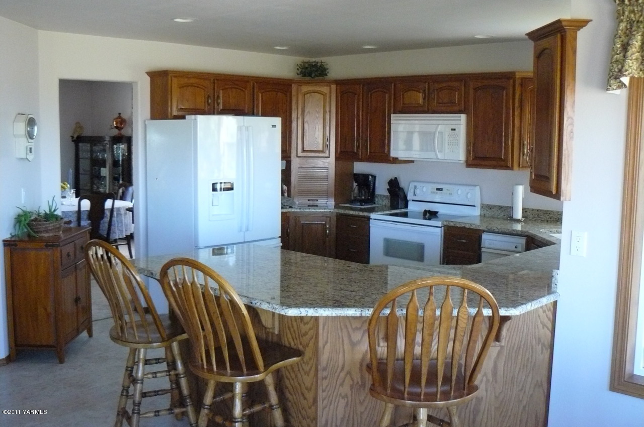 12074 Mieras Road Moxee, WA 98936 - Photo 2 of 22 a kitchen with stainless steel appliances granite countertop a stove a refrigerator a sink a dining table and chairs