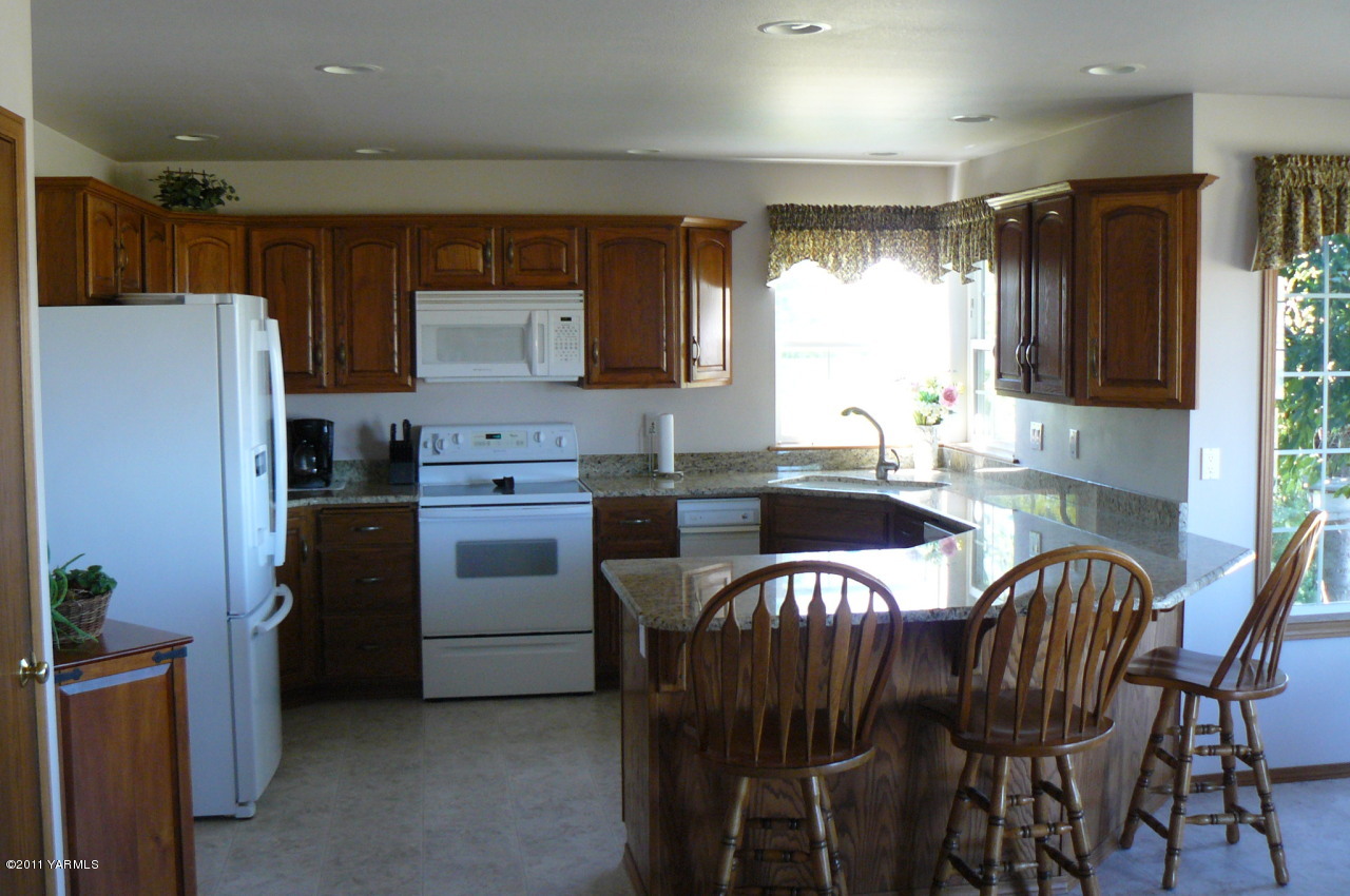 12074 Mieras Road Moxee, WA 98936 - Photo 16 of 22 a kitchen with a table chairs refrigerator and microwave