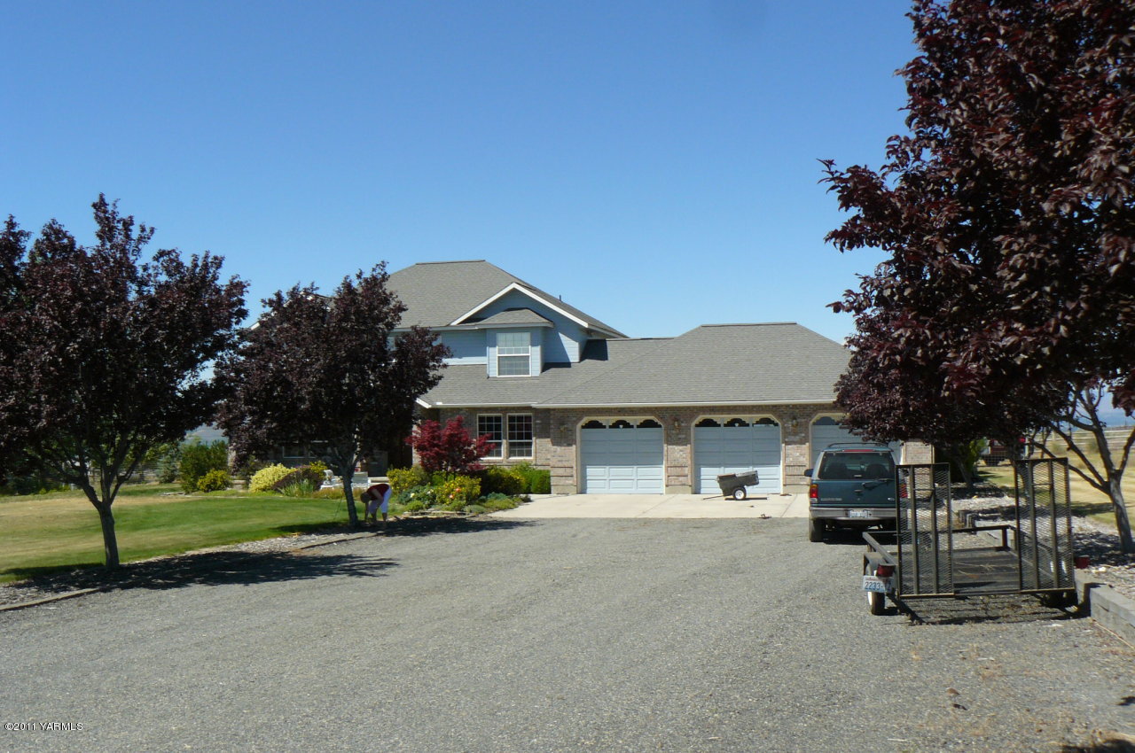 12074 Mieras Road Moxee, WA 98936 - Photo 5 of 22 a front view of a house with a garden and trees