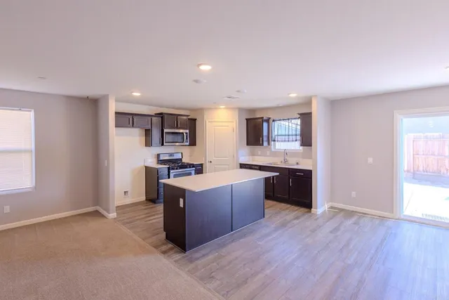 a large kitchen with stainless steel appliances granite countertop a large counter top and wooden floors