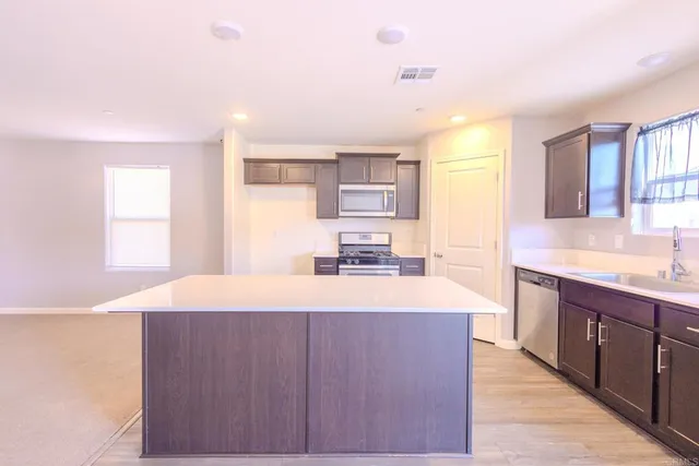 a large kitchen with kitchen island a sink dishwasher a stove and a refrigerator with wooden floor