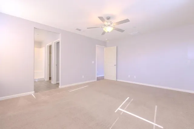 a view of an empty room with a chandelier fan