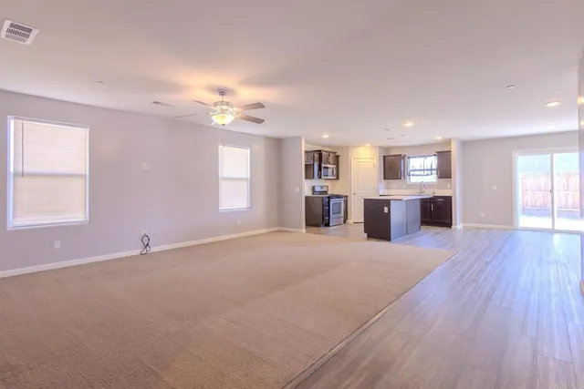 a view of an empty room with window and wooden floor