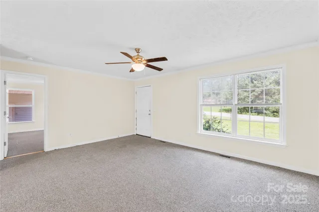 an empty room with windows and fan