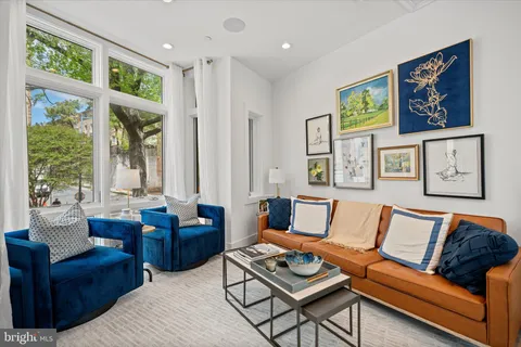 a living room with furniture large window and wall painting