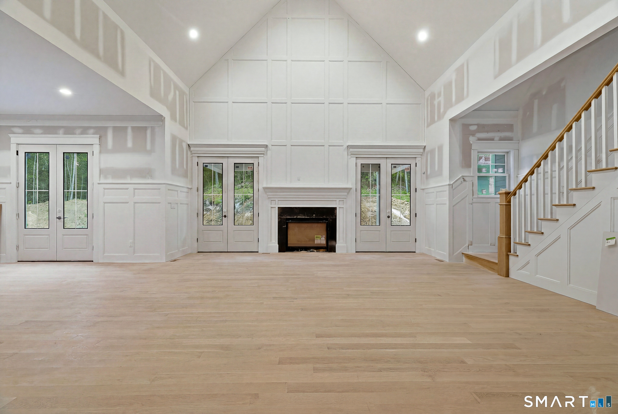41 B Whippoorwill Road Old Lyme, CT 06371 - Photo 3 of 12 Anchored by a fireplace, soaring vaulted ceilings, and extensive custom millwork, the great room serves as the heart of the home, seamlessly connecting the chef's kitchen to the left and the private main-level primary suite to the right