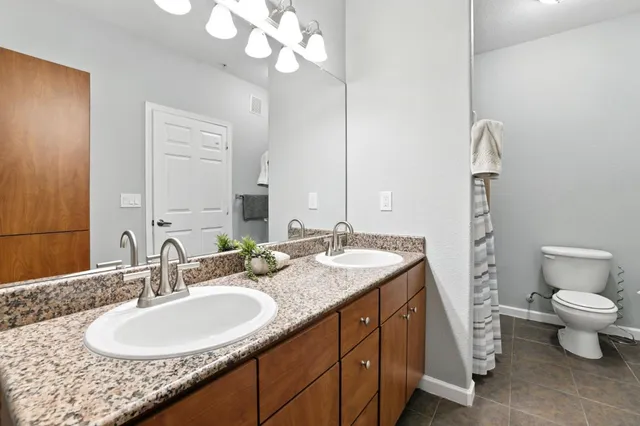 a bathroom with a granite countertop sink a toilet and a mirror
