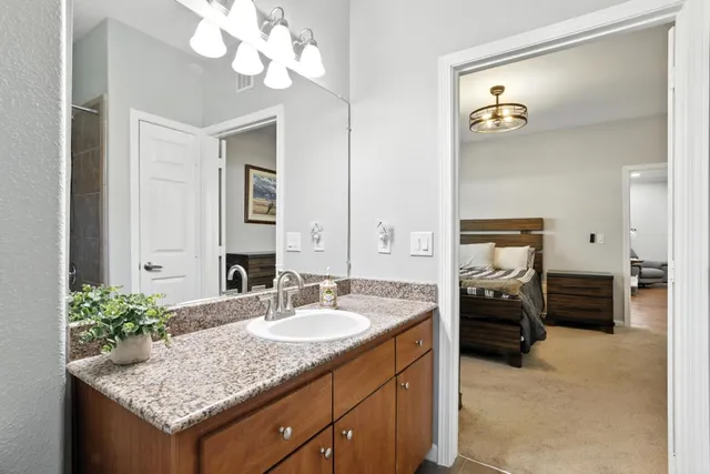 a en suite bathroom with a granite countertop sink and a mirror