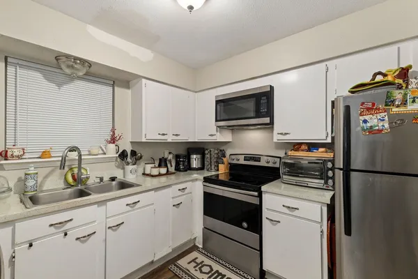 a kitchen with refrigerator a sink a stove and cabinets