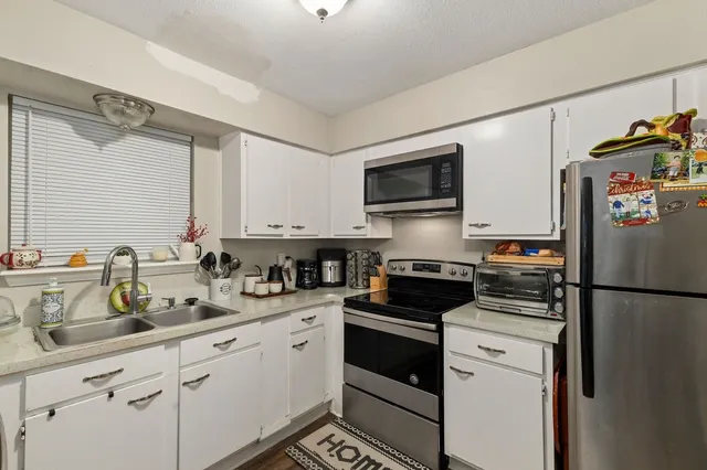 a kitchen with refrigerator a sink a stove and cabinets