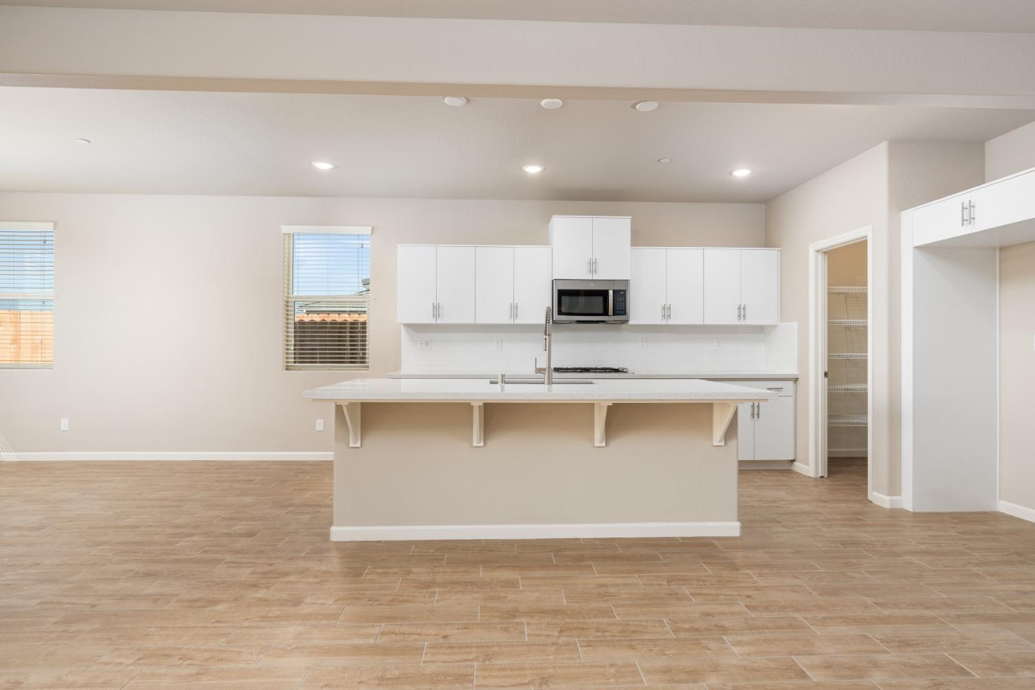 952 Pinnacle Drive Madera, CA 93636 - Photo 14 of 32 a large kitchen with stainless steel appliances granite countertop a stove a sink and white cabinets