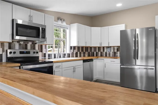 a kitchen with granite countertop a refrigerator stove and microwave