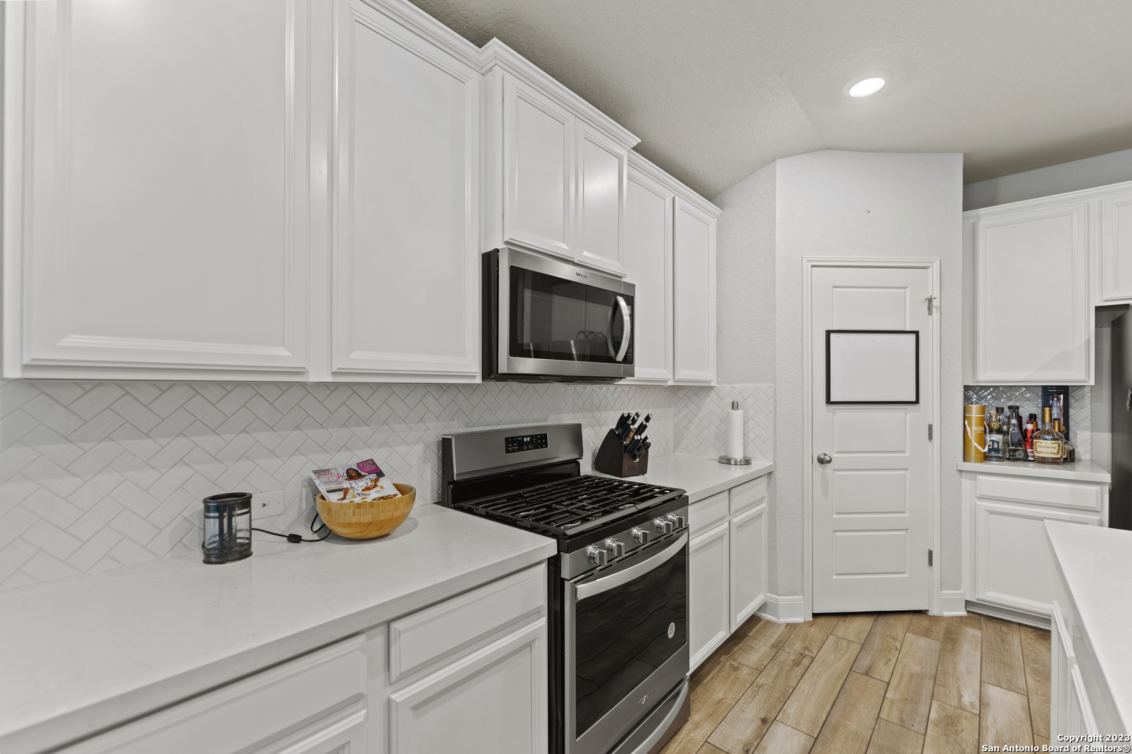 12136 Icon Ridge San Antonio, TX 78253 - Photo 5 of 26 a kitchen with granite countertop white cabinets stainless steel appliances and wooden floor