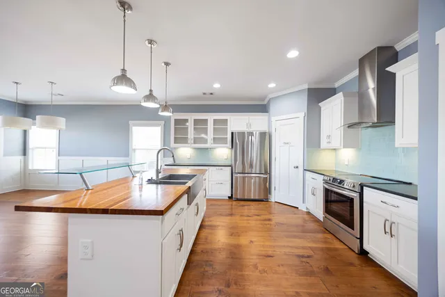 a kitchen with stainless steel appliances granite countertop a sink a stove and a wooden floors