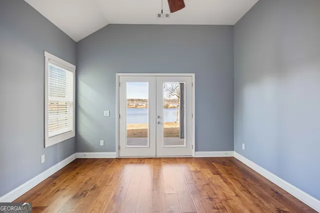 an empty room with wooden floor and windows