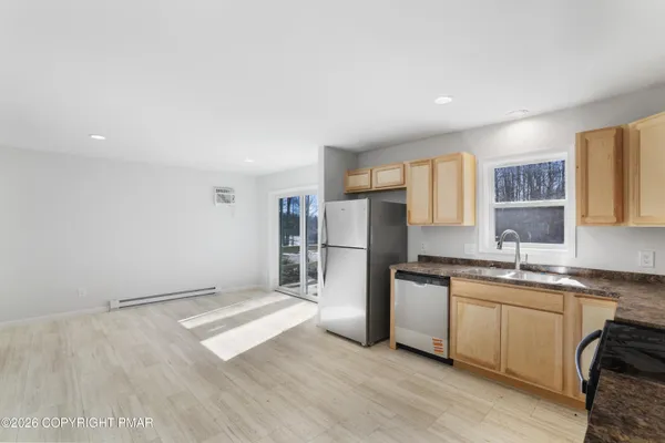 a kitchen with stainless steel appliances a sink a stove a refrigerator cabinets and a window