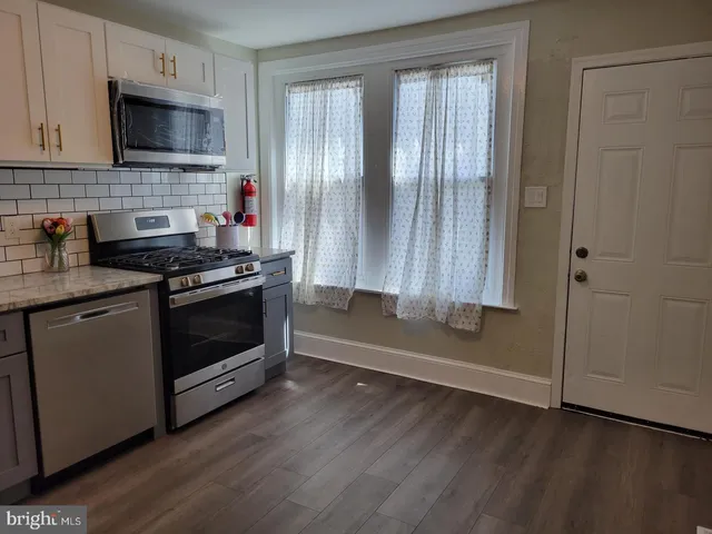 a kitchen with granite countertop wooden cabinets stainless steel appliances and a window