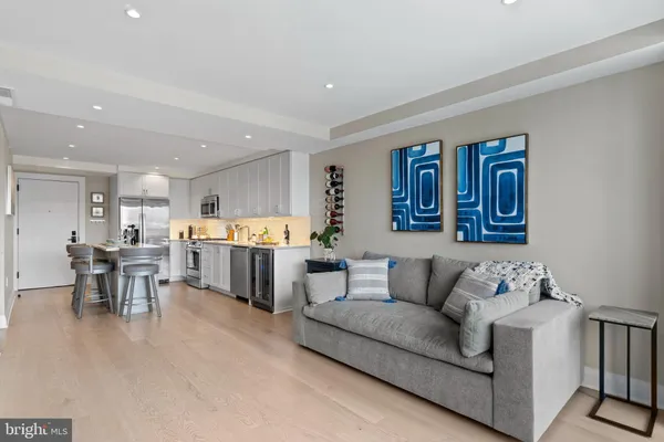a living room with furniture kitchen view and a wooden floor