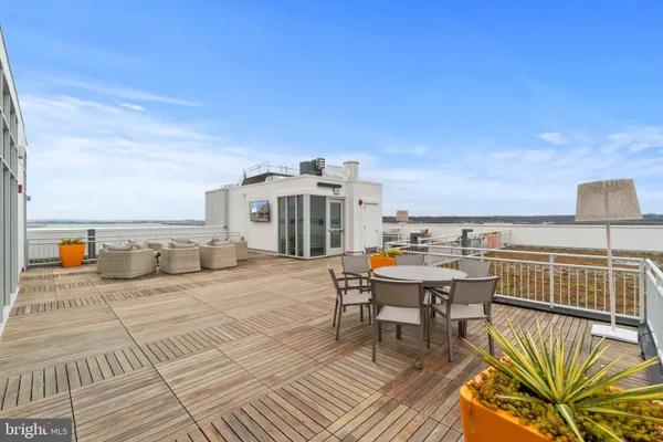 a view of a roof deck with table and chairs a barbeque with wooden floor and city view
