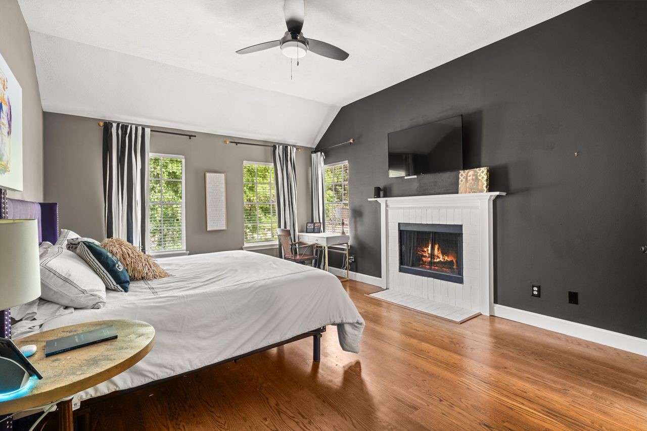 36 Wind River Drive Conroe, TX 77384 - Photo 32 of 45 This spacious bedroom features a warm fireplace, dark accent wall, and hardwood floors. Large windows provide ample natural light, and the ceiling fan adds comfort.