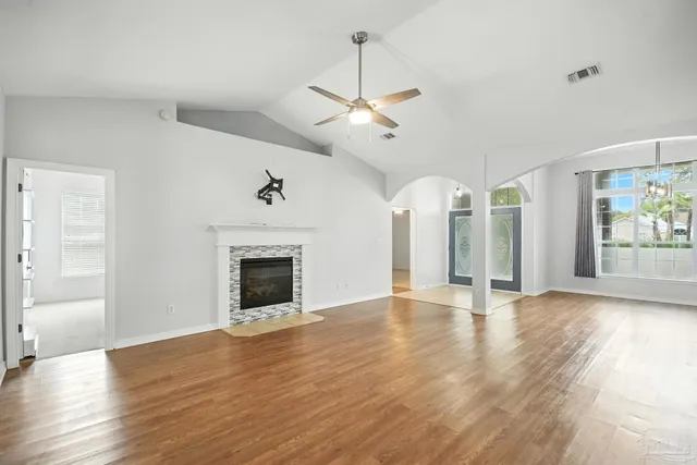 a view of an empty room with wooden floor fireplace and a window