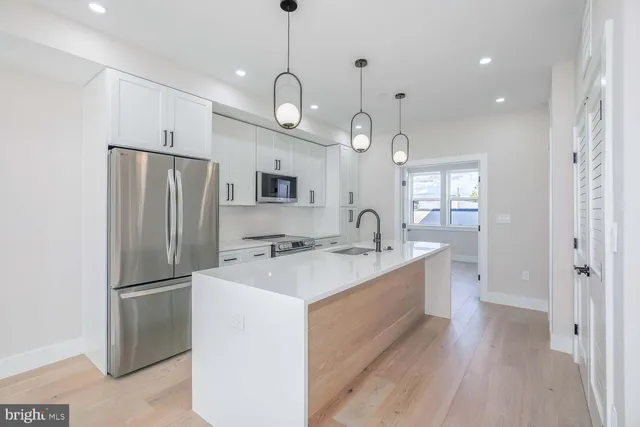a kitchen with refrigerator a sink and wooden floor