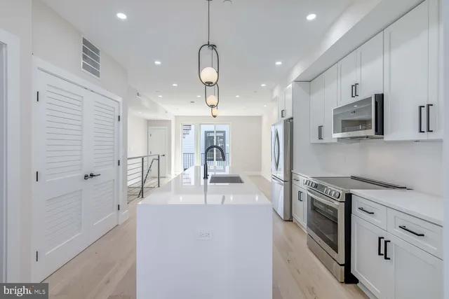 a kitchen with stainless steel appliances granite countertop a refrigerator a stove oven a sink dishwasher and white cabinets with wooden floor