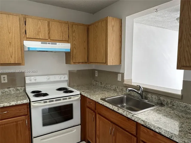 a kitchen with granite countertop a sink stove and cabinets