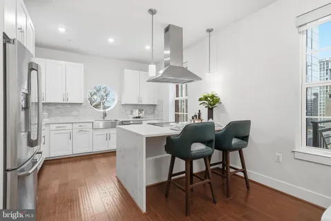 a kitchen with stainless steel appliances kitchen island granite countertop a table chairs and a wooden floor