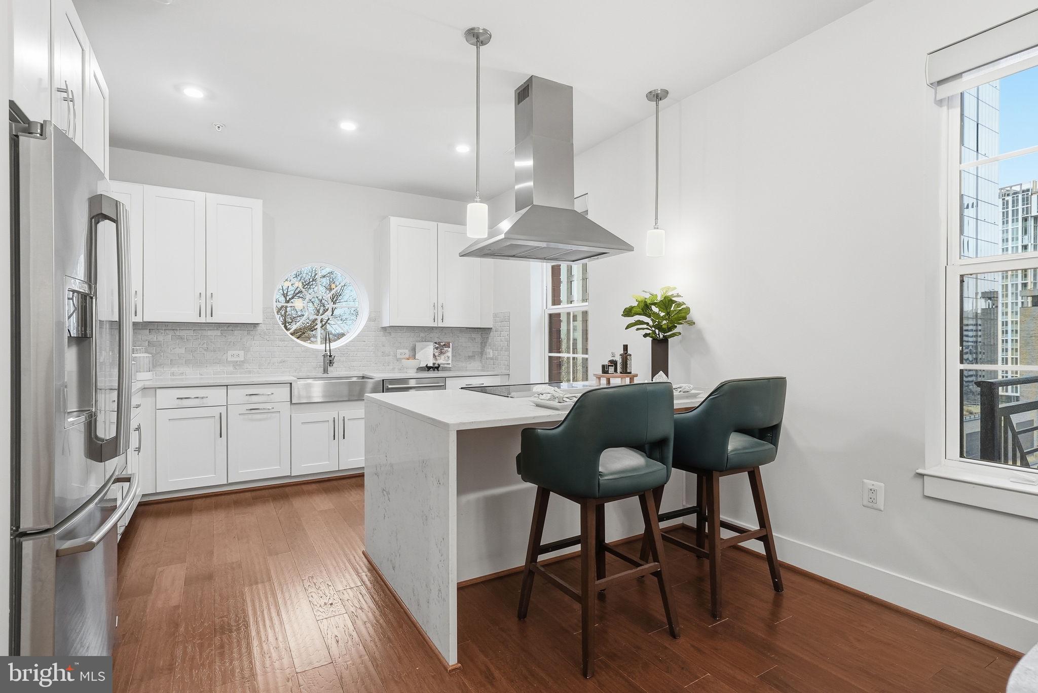 1411 Key Boulevard, Unit 505 Arlington, VA 22209 - Photo 5 of 26 a kitchen with stainless steel appliances kitchen island granite countertop a table chairs and a wooden floor