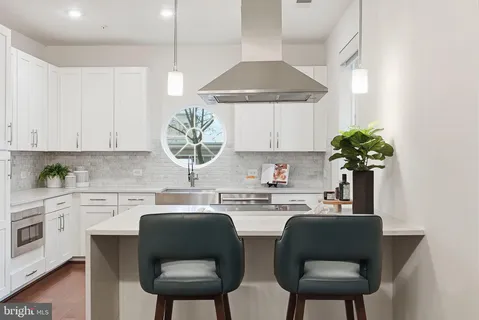 a kitchen with stainless steel appliances a table and chairs in it