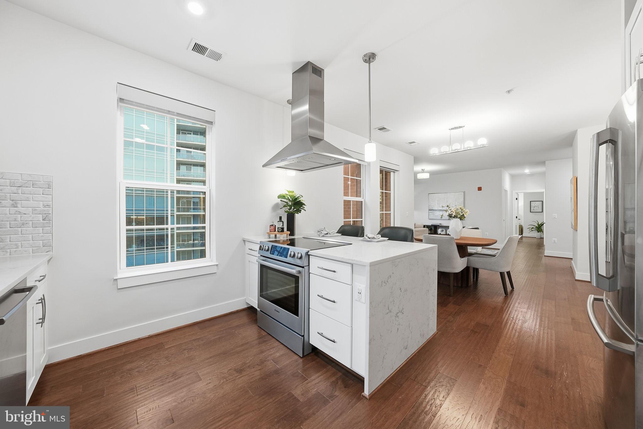 1411 Key Boulevard, Unit 505 Arlington, VA 22209 - Photo 7 of 26 a kitchen with a stove a window and chairs