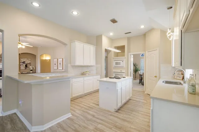 a large kitchen with a lot of counter space and wooden floor