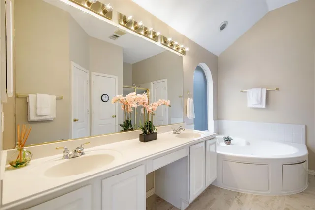 a bathroom with a double vanity sink mirror and bathtub