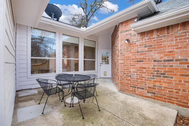 a patio with table and chairs and potted plants