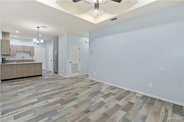 a view of kitchen and empty room with wooden floor