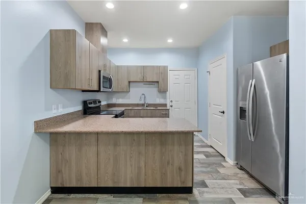 a kitchen with kitchen island a stove a refrigerator and a sink