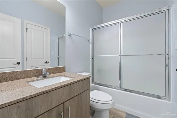 a bathroom with a granite countertop sink toilet and a mirror