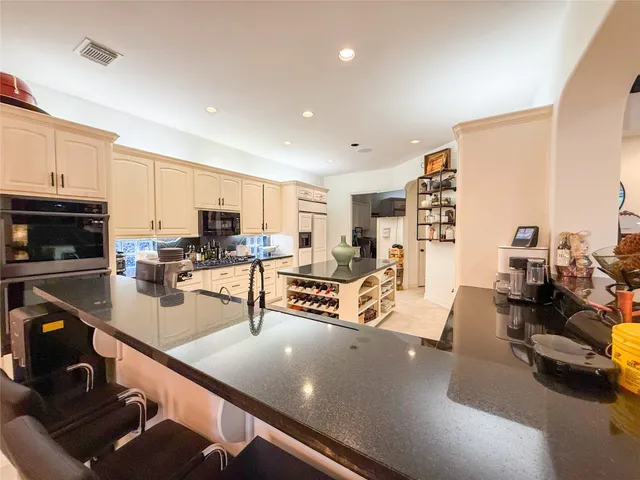 a living room with stainless steel appliances furniture and a kitchen view