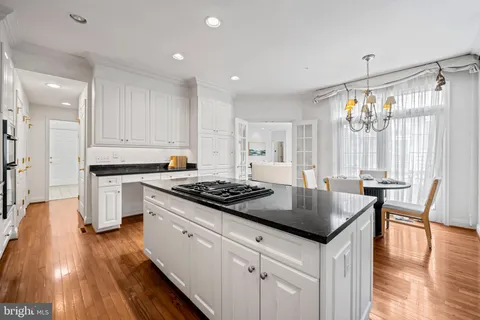 a kitchen with granite countertop a stove a sink dishwasher a refrigerator and white cabinets with wooden floor