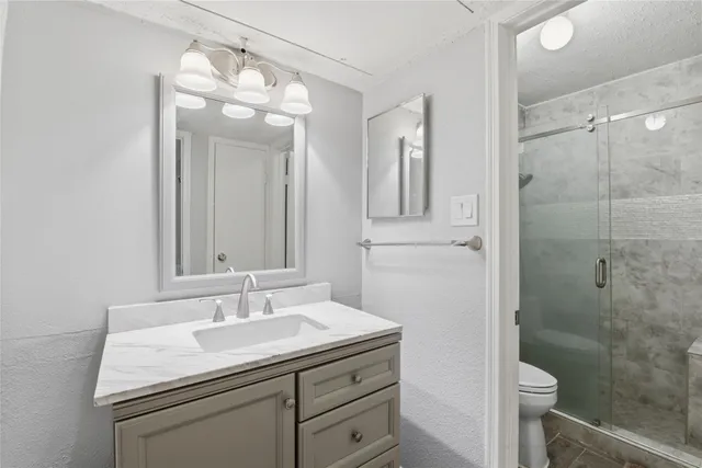 a bathroom with a sink a toilet and shower