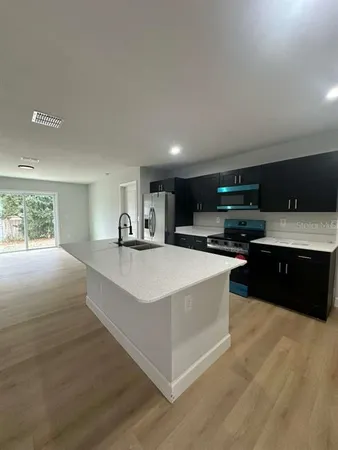 a large white kitchen with kitchen island a sink dishwasher a stove and a refrigerator with wooden floor