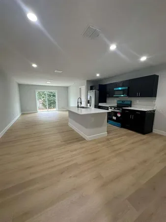 a large kitchen with kitchen island a sink dishwasher a stove and a refrigerator with wooden floor