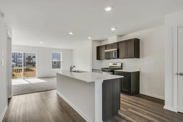 a kitchen with stainless steel appliances a sink dishwasher a stove top oven a refrigerator with wooden floors and cabinets