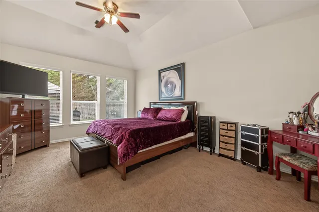 a spacious bedroom with a bed and a flat tv screen