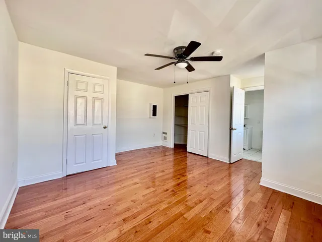 a view of empty room with wooden floor and ceiling fan
